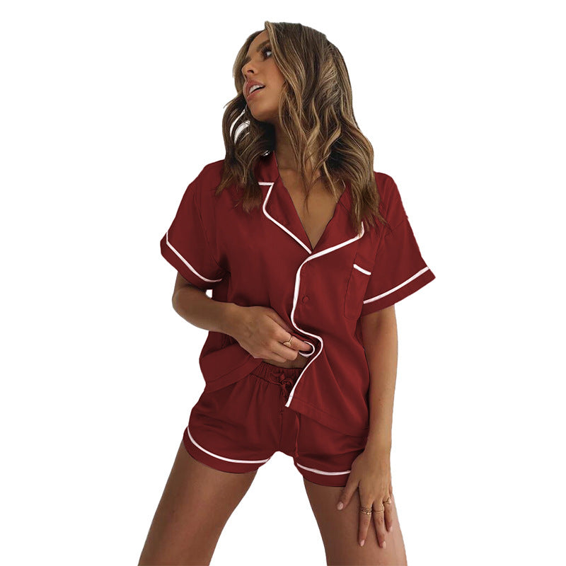 Woman wearing a soft satin pajama set featuring a short-sleeved button-up shirt and matching shorts, available in pink, red, green, black, and blue—lightweight, elegant, and perfect for sleepwear.