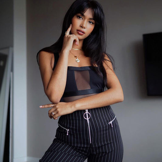 Chic sheer black top with thick straps, paired with high-waisted pinstripe pants featuring zipper details – stylish, edgy, and perfect for trendy outfits.
