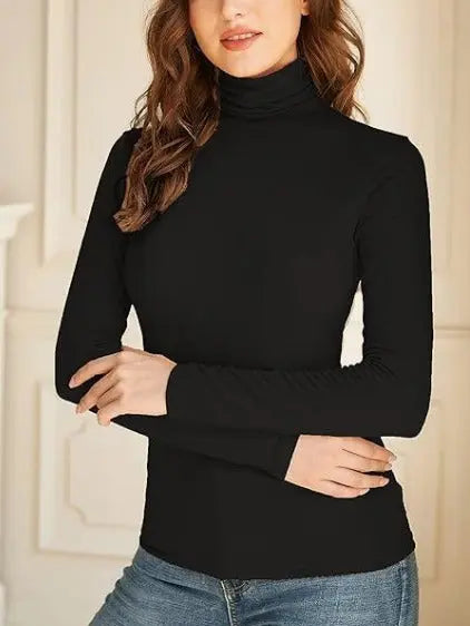 Woman wearing an black turtleneck long-sleeve top paired with blue jeans, standing in front of decorative wall panels—sleek, stylish, and perfect for layering.