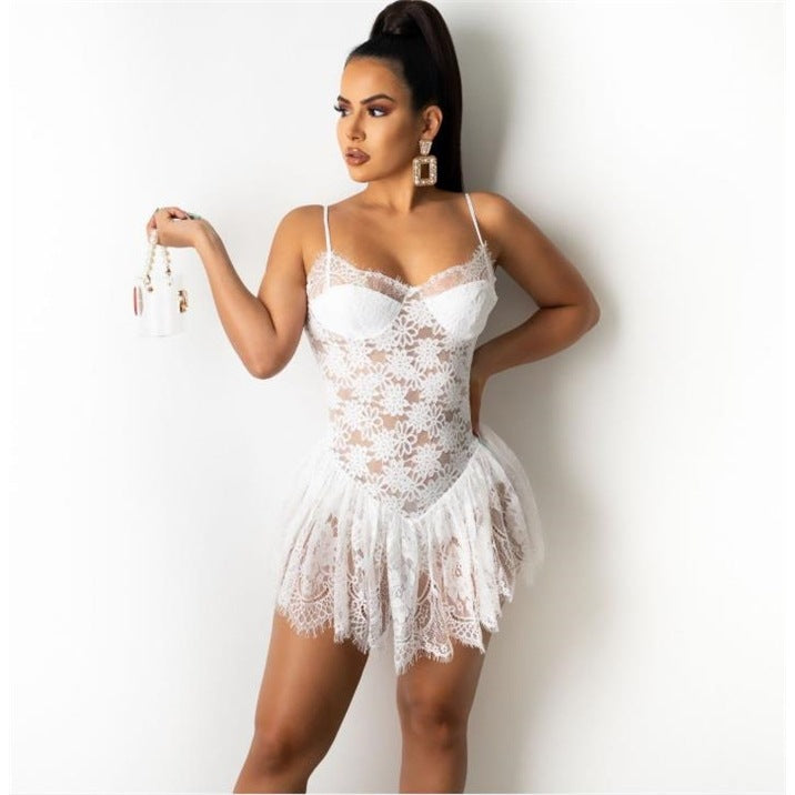 Front view of a white lace mini slip dress with floral patterns, thin straps, and semi-transparent fabric, paired with a small white chain-strap handbag in a studio-lit setting