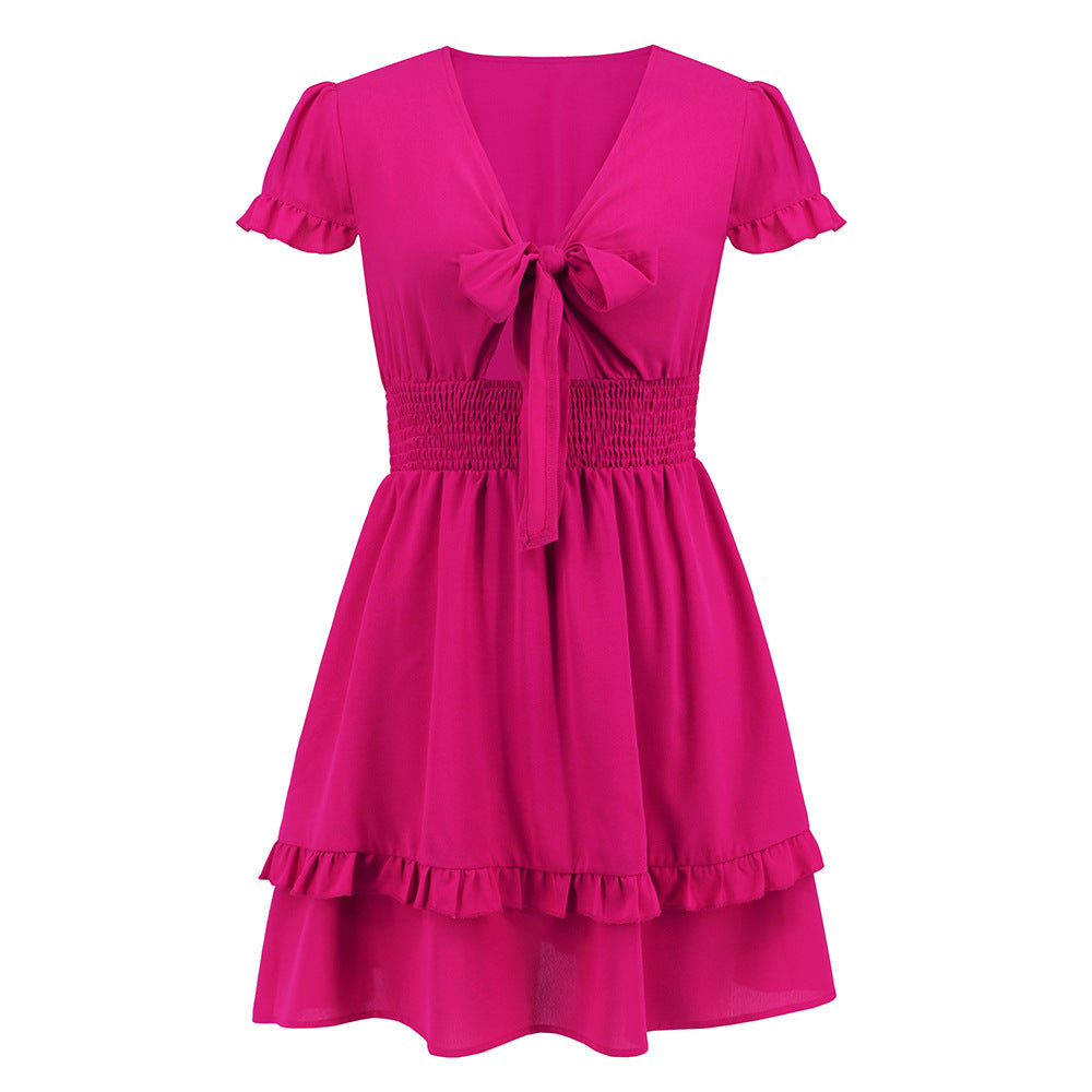 A vibrant ruffled dress featuring a bow-tie neckline, smocked waist, and flared layered hem, styled for a romantic and elegant look