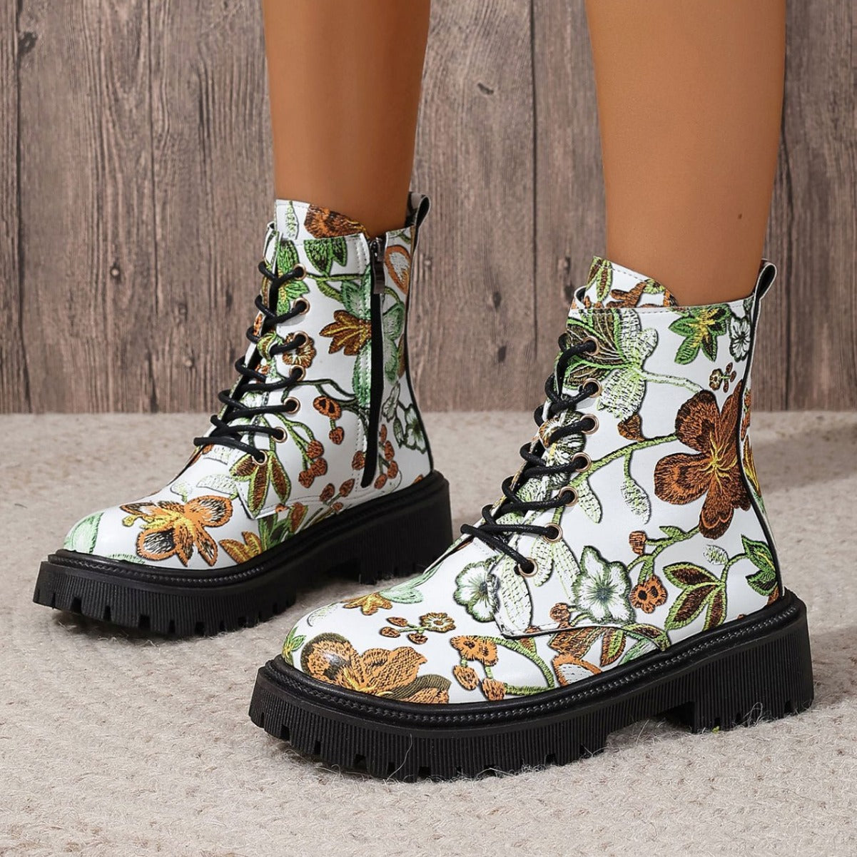 White combat-style boots with a vibrant floral pattern, black laces, deep-tread black soles, and side zippers—bold, stylish, and perfect for any outfit.