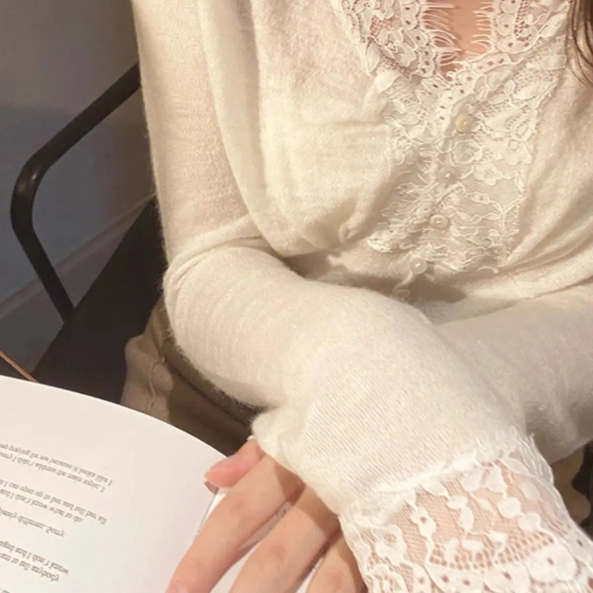 White sweater with intricate floral lace detailing around the neckline and cuffs, styled with delicate accessories—elegant, cozy, and perfect for both casual and dressy outfits.