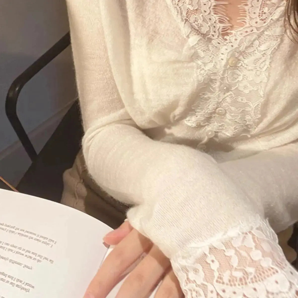 White sweater with intricate floral lace detailing around the neckline and cuffs, styled with delicate accessories—elegant, cozy, and perfect for both casual and dressy outfits.