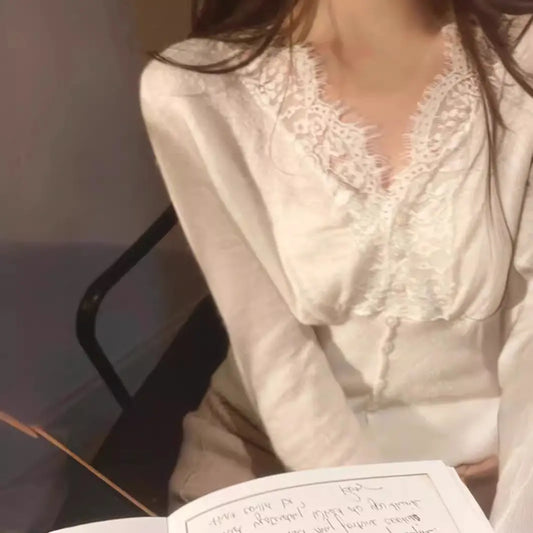 White sweater with intricate floral lace detailing around the neckline and cuffs, styled with delicate accessories—elegant, cozy, and perfect for both casual and dressy outfits.