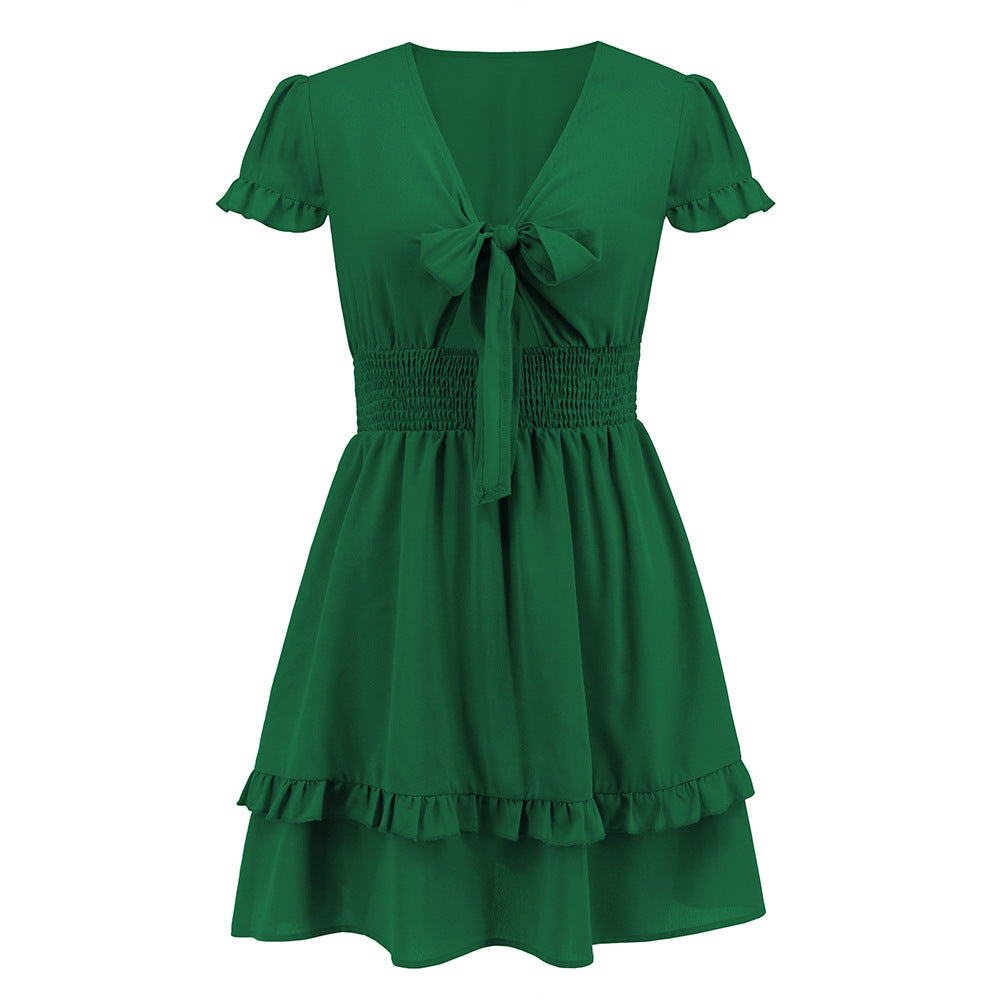 A vibrant ruffled dress featuring a bow-tie neckline, smocked waist, and flared layered hem, styled for a romantic and elegant look