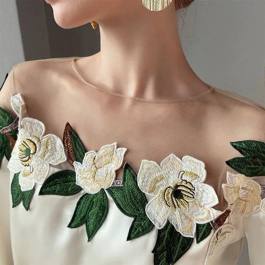 Woman wearing an off-the-shoulder blouse with white floral embroidery and puffed sleeves, paired with a textured high-waist skirt—sophisticated, chic, and perfect for both casual and dressy outfits.