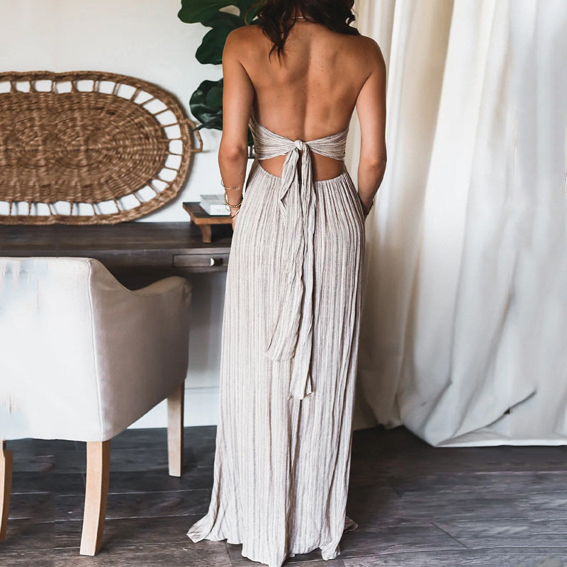 Backless solid-colour maxi dress with U-neckline and thin straps, worn with a woven basket bag in a light-filled interior setting