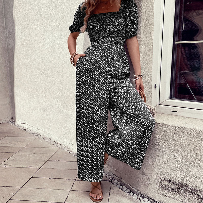 Elegant black floral jumpsuit with square neckline, puffed short sleeves, and wide-leg pants – stylish, breathable, and perfect for casual or chic occasions.