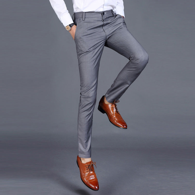Multiple views of structured tailored trousers in navy, grey, black, and additional colours, styled with a white shirt and brown shoes, highlighting pleats, tapered legs, and buttoned back pockets