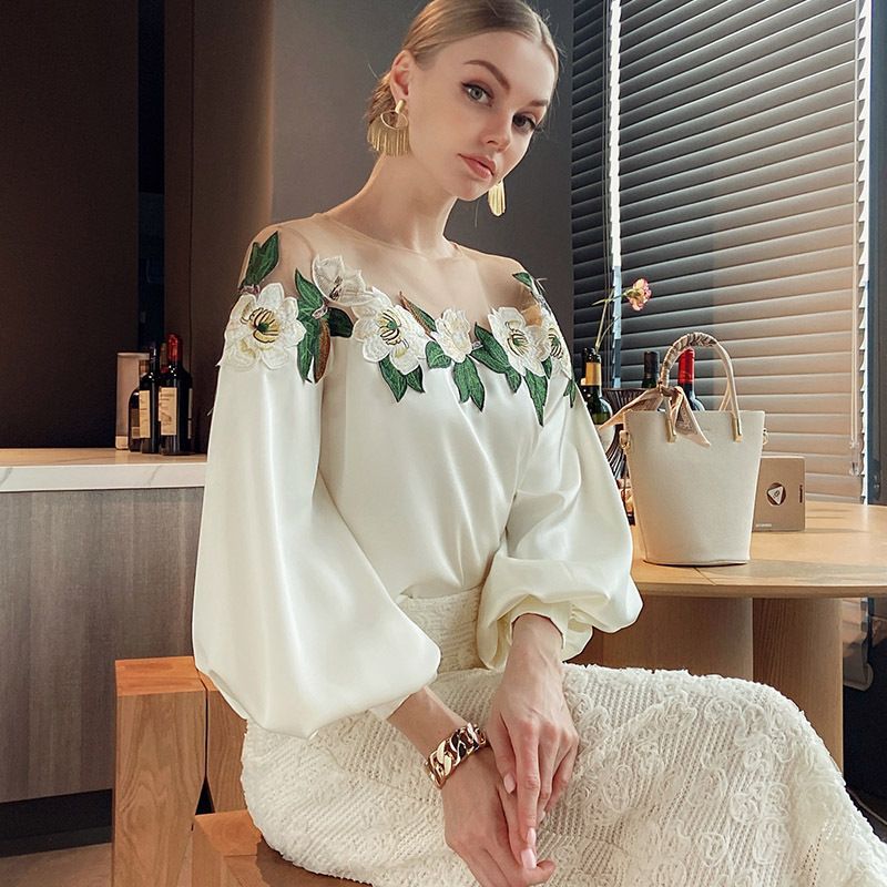 Woman wearing an off-the-shoulder blouse with white floral embroidery and puffed sleeves, paired with a textured high-waist skirt—sophisticated, chic, and perfect for both casual and dressy outfits.