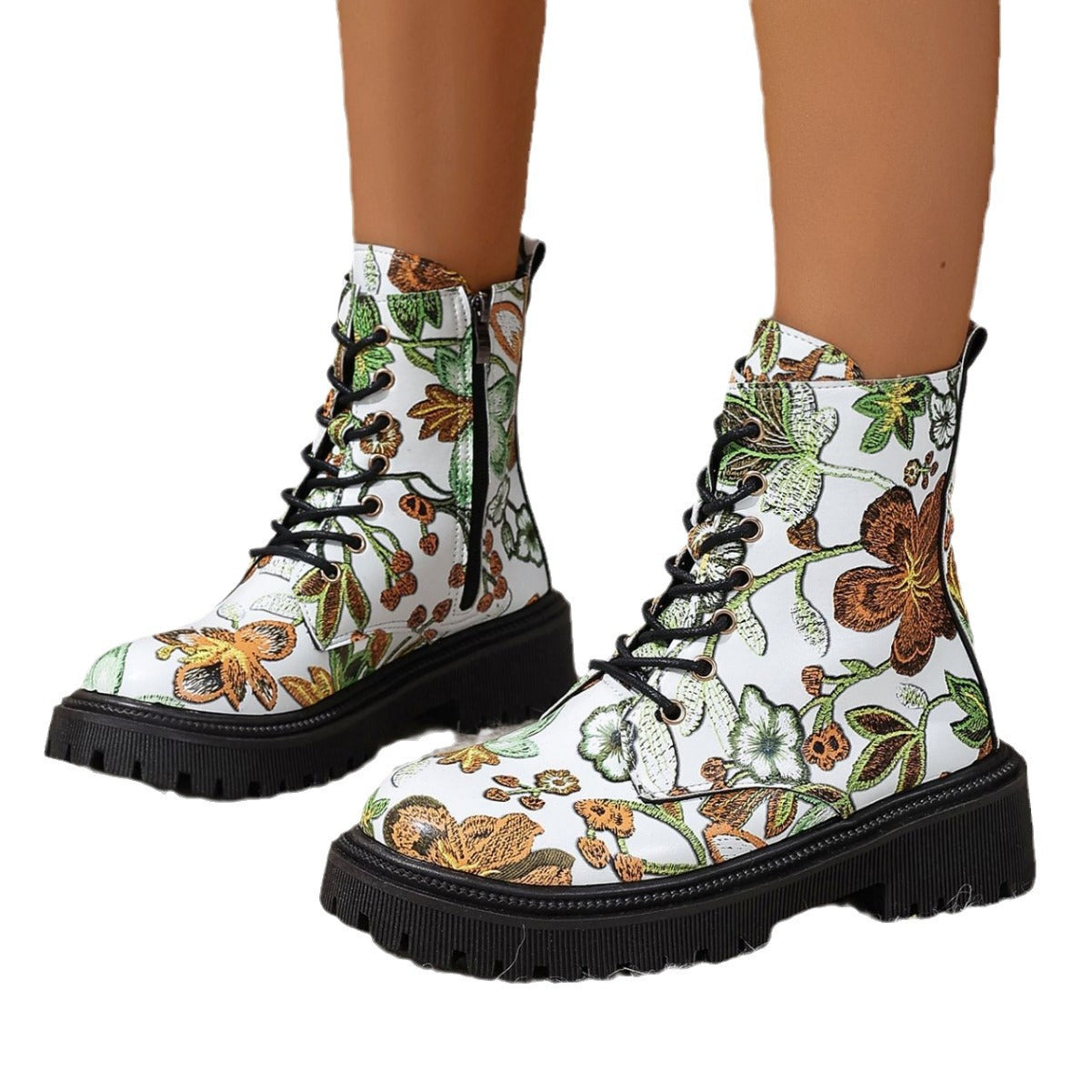 White combat-style boots with a vibrant floral pattern, black laces, deep-tread black soles, and side zippers—bold, stylish, and perfect for any outfit.