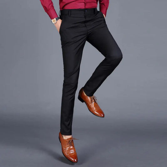 Multiple views of structured tailored trousers in navy, grey, black, and additional colours, styled with a white shirt and brown shoes, highlighting pleats, tapered legs, and buttoned back pockets