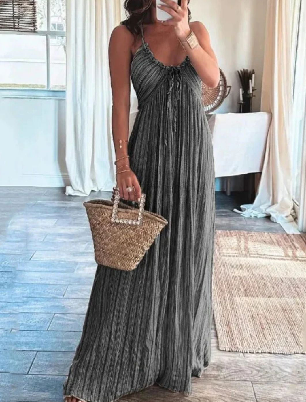 Backless solid-colour maxi dress with U-neckline and thin straps, worn with a woven basket bag in a light-filled interior setting