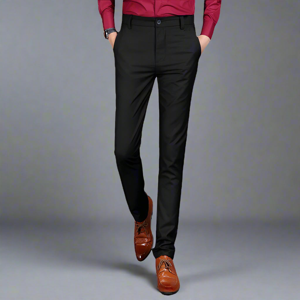 Multiple views of structured tailored trousers in navy, grey, black, and additional colours, styled with a white shirt and brown shoes, highlighting pleats, tapered legs, and buttoned back pockets