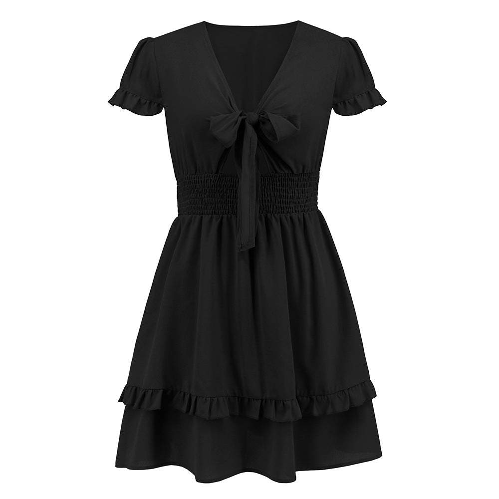 A vibrant ruffled dress featuring a bow-tie neckline, smocked waist, and flared layered hem, styled for a romantic and elegant look