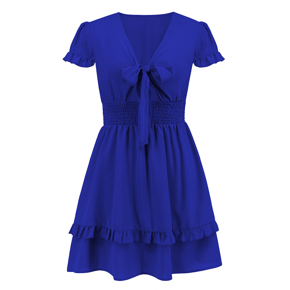A vibrant ruffled dress featuring a bow-tie neckline, smocked waist, and flared layered hem, styled for a romantic and elegant look