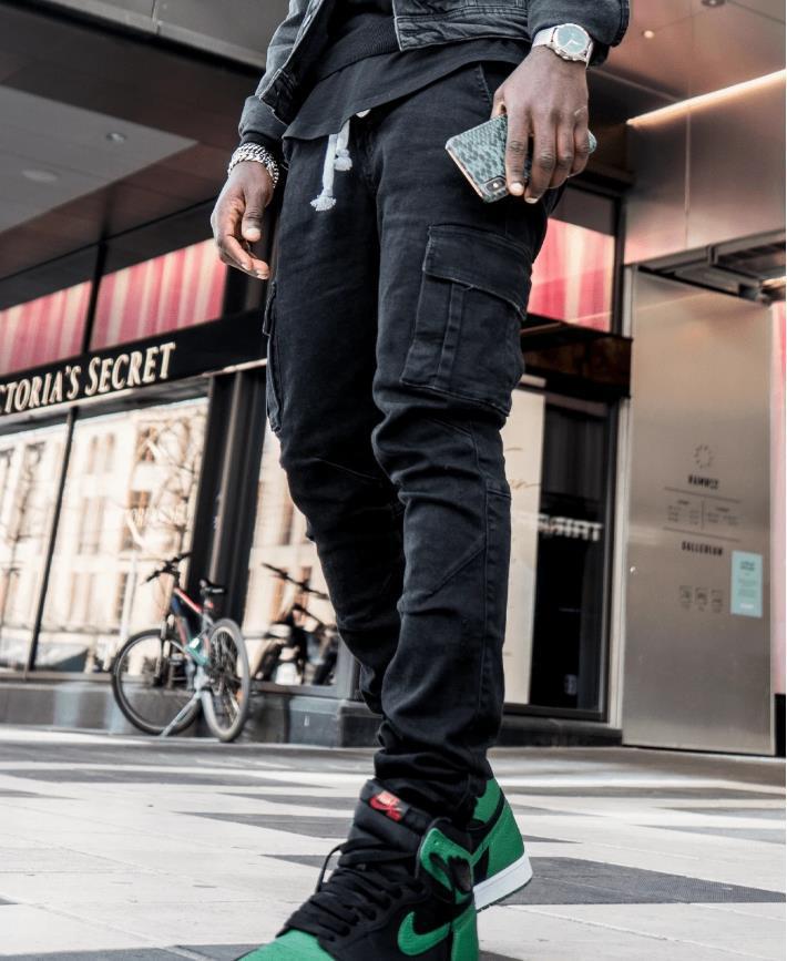 Black and light blue denim cargo pants with multiple pockets and visible seam details, laid flat on a textured surface