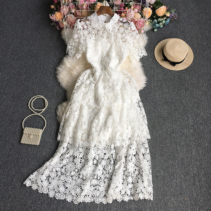 White lace dress with a hat, handbag, and flowers on a dark surface