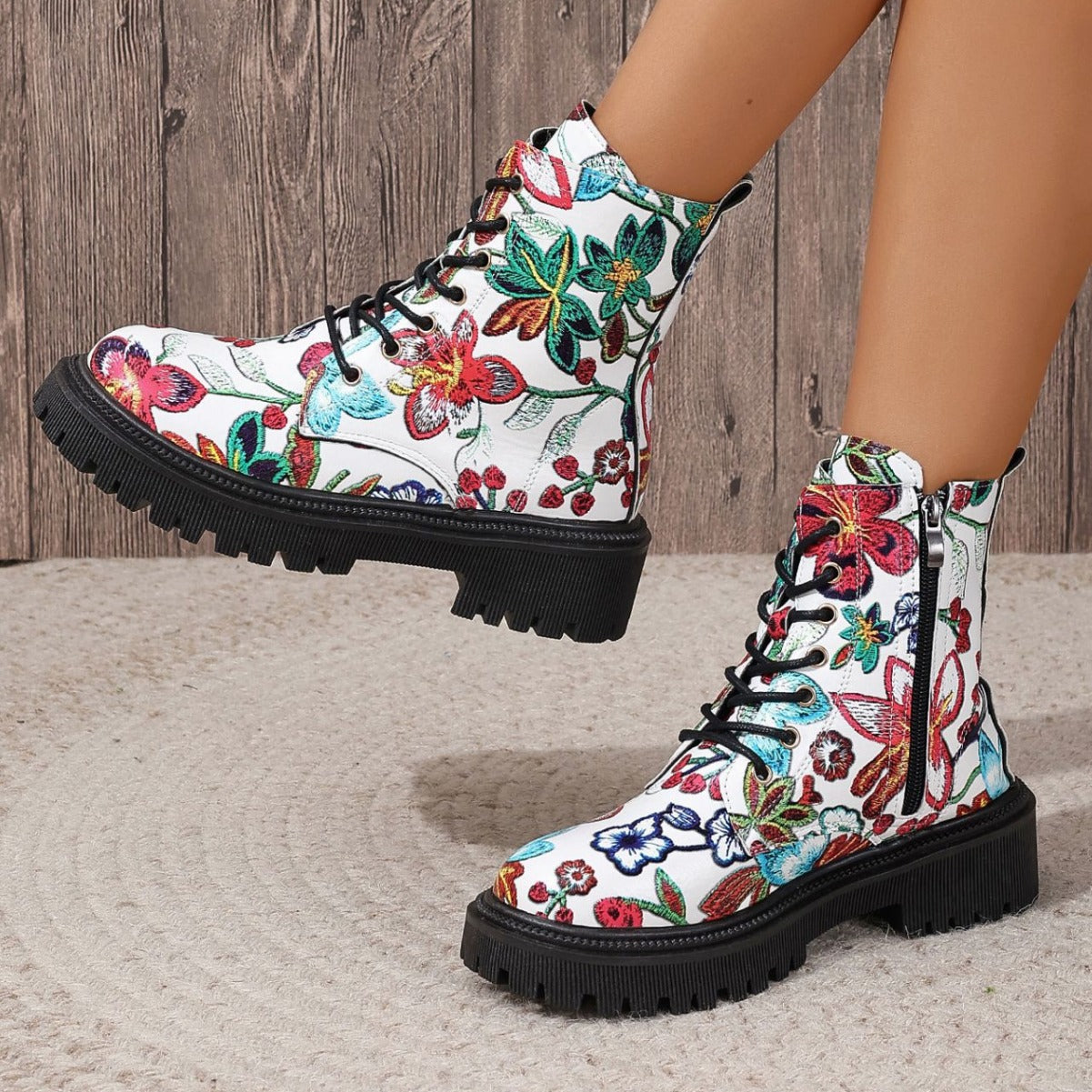 White combat-style boots with a vibrant floral pattern, black laces, deep-tread black soles, and side zippers—bold, stylish, and perfect for any outfit.