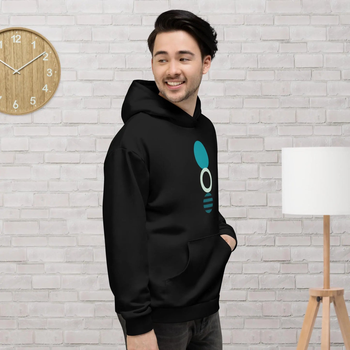 Black hoodie featuring a bold teal and white circular geometric design, with a front pocket and adjustable metal-tipped drawstring hood—modern, stylish, and perfect for everyday wear.