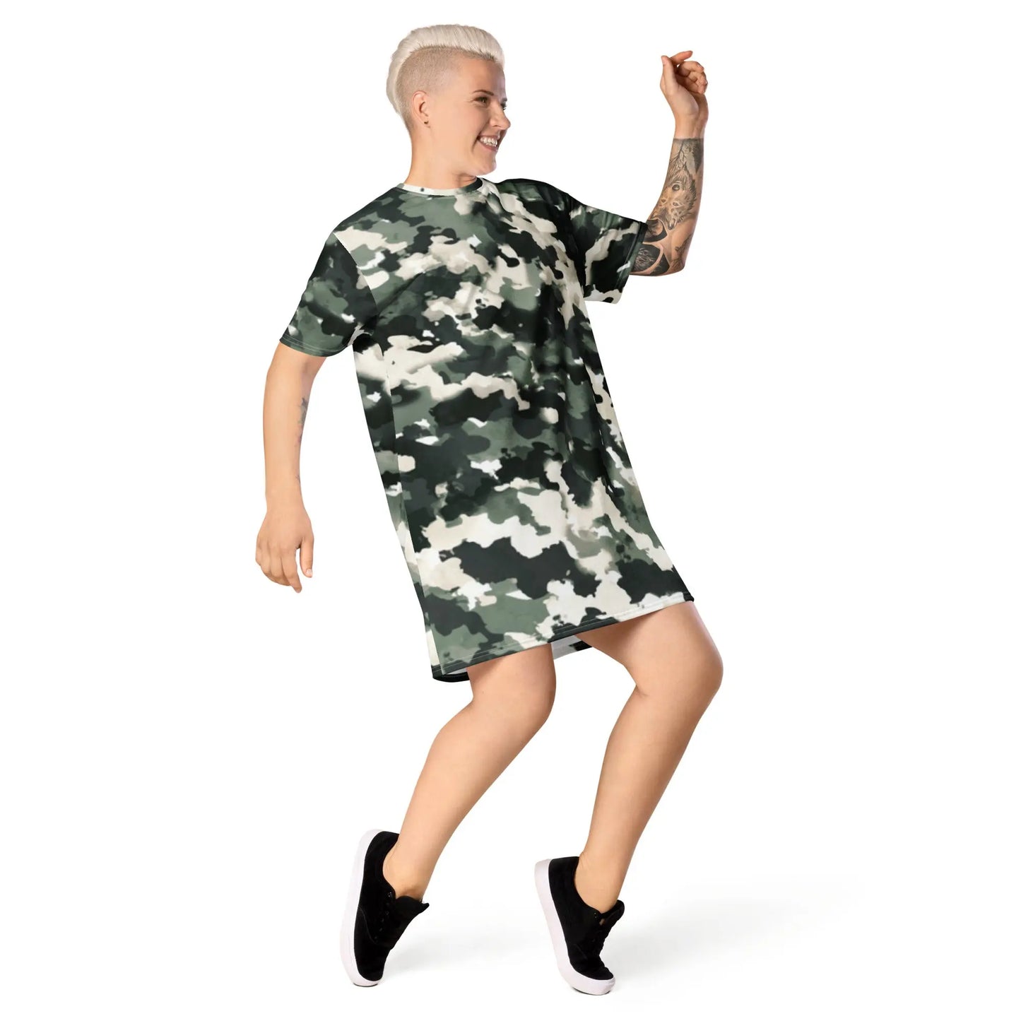 Person wearing a camouflage-patterned t-shirt dress featuring green, black, and white shades, paired with black sneakers with white soles—stylish, sporty, and perfect for casual streetwear.