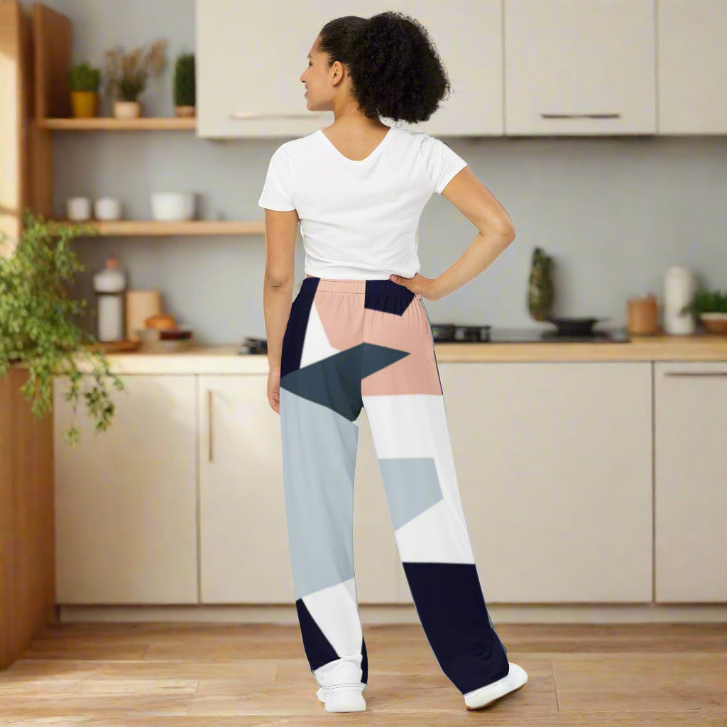 Woman wearing high-waist wide-leg pants with a geometric print in navy, light blue, pink, and white—styled with a beige long-sleeve shirt for an effortlessly chic look.