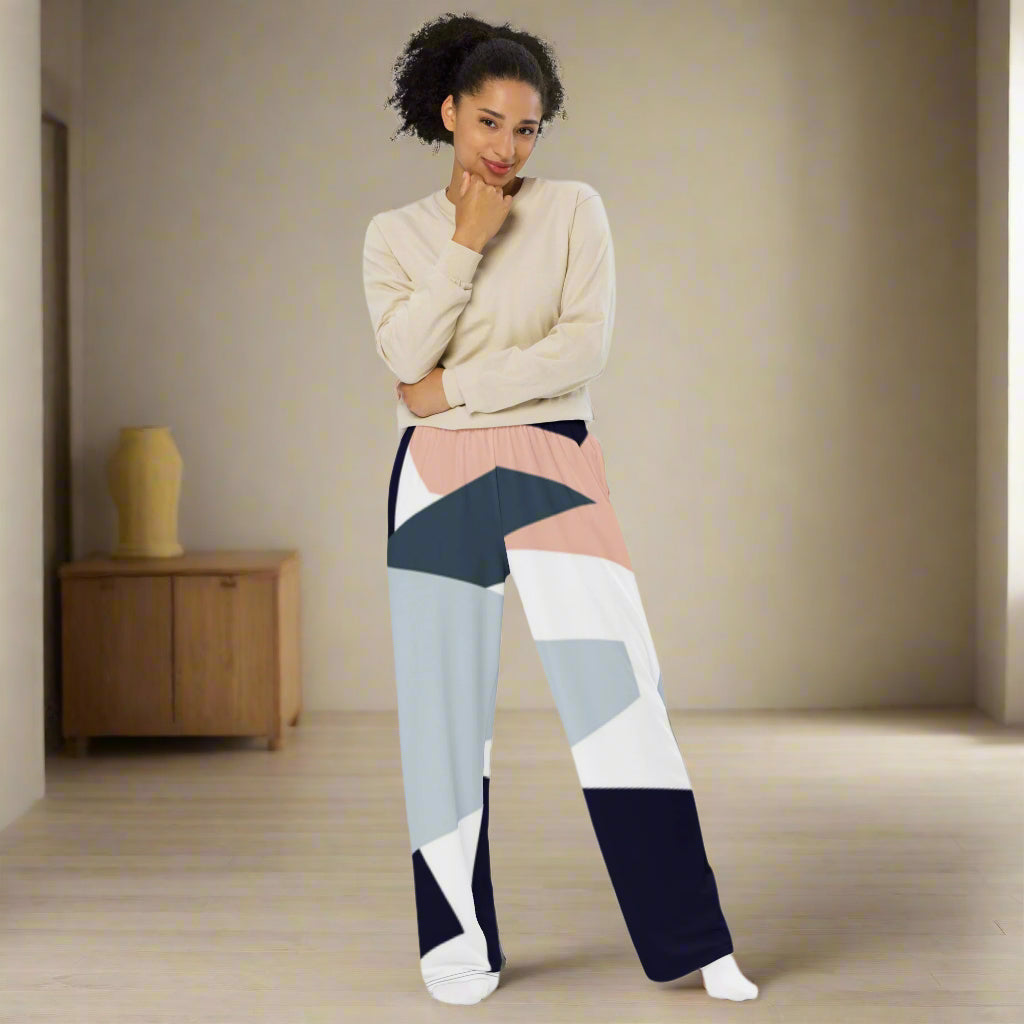 Woman wearing high-waist wide-leg pants with a geometric print in navy, light blue, pink, and white—styled with a beige long-sleeve shirt for an effortlessly chic look.