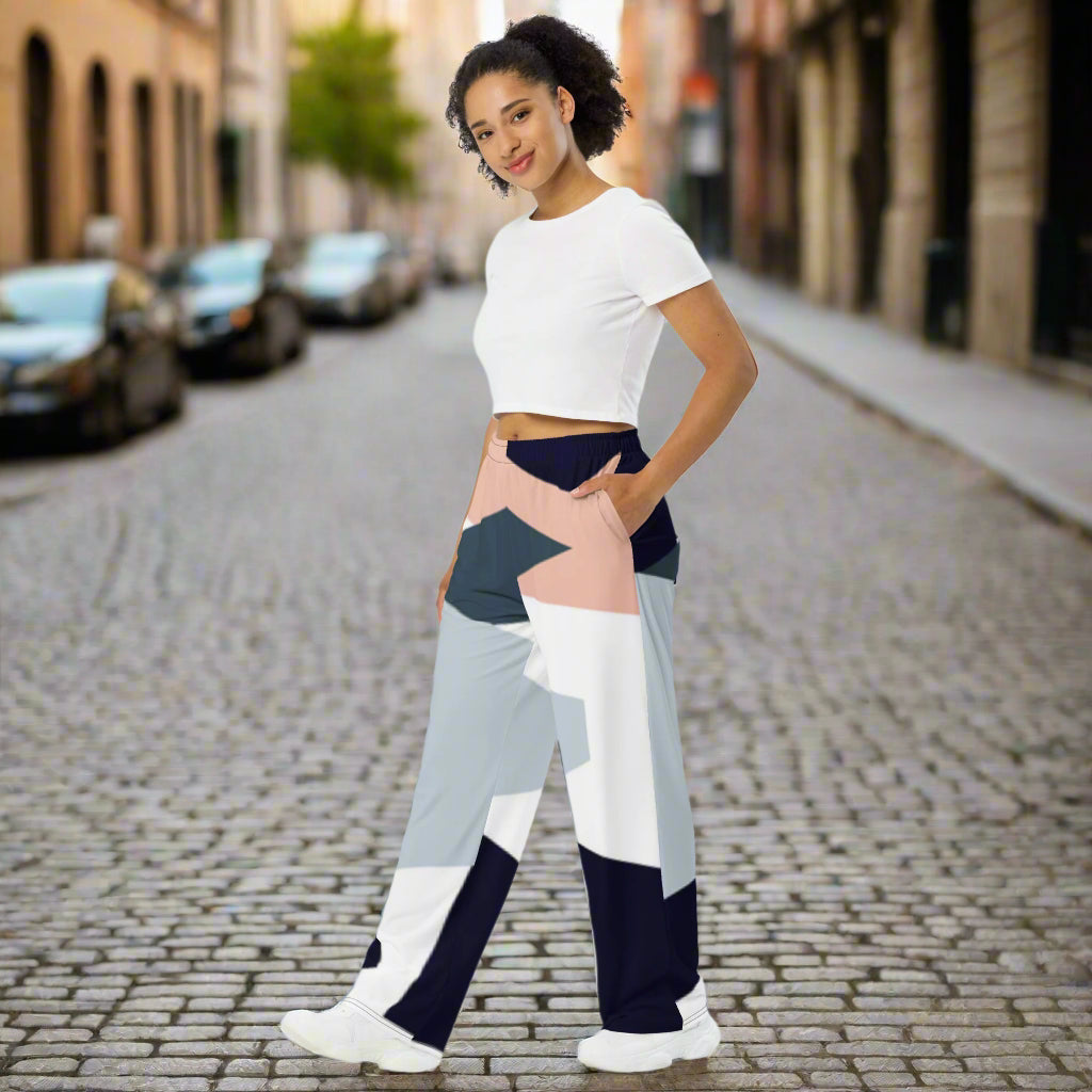 Woman wearing high-waist wide-leg pants with a geometric print in navy, light blue, pink, and white—styled with a beige long-sleeve shirt for an effortlessly chic look.
