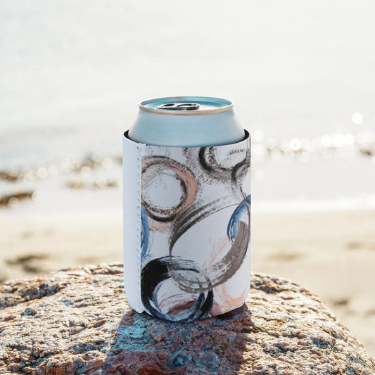 Can wrapped in an abstract-designed sleeve featuring swirls and strokes in blue, peach, and black, placed on a rock by the beach—modern, artistic, and perfect for casual drink accessories