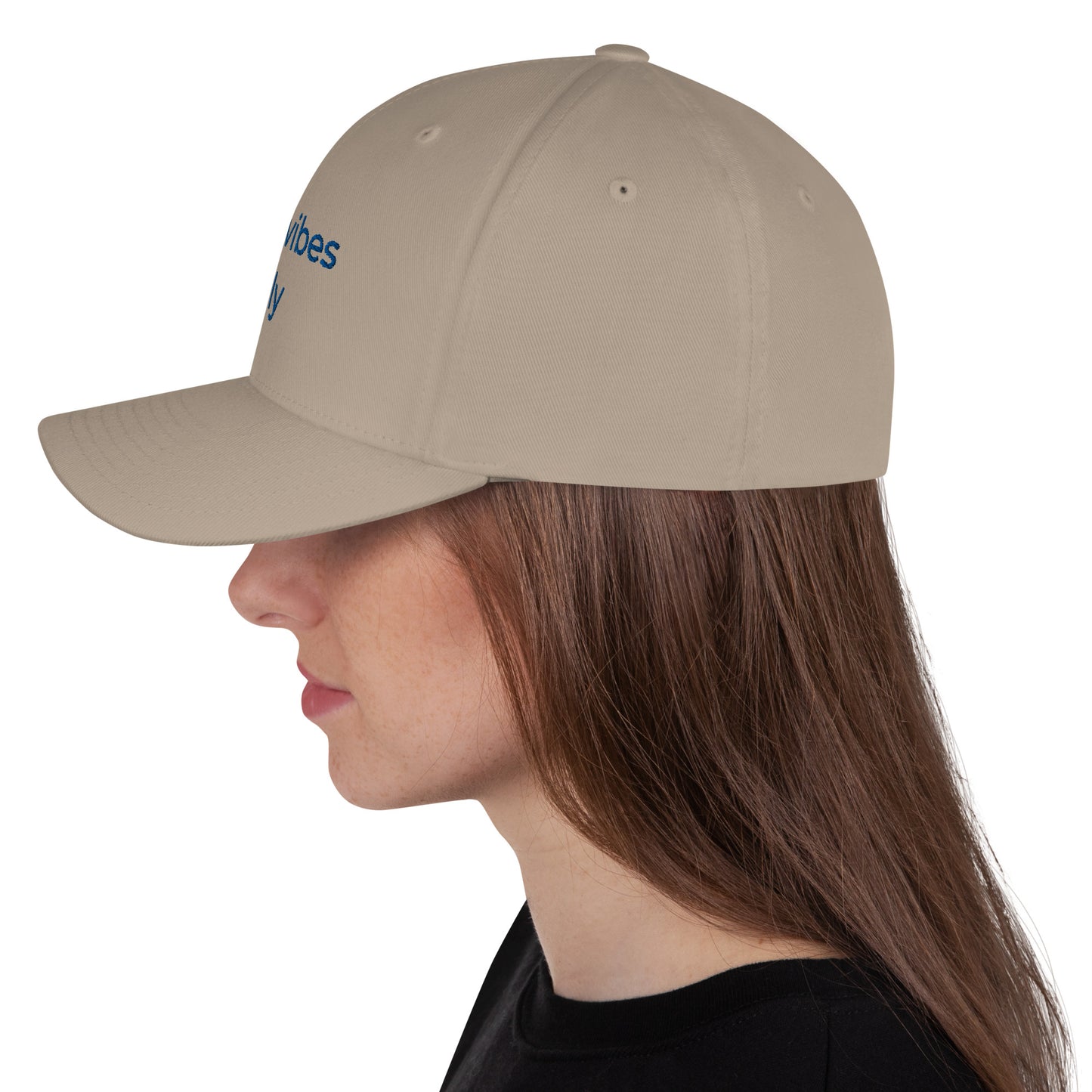 White baseball cap featuring embroidered text reading ‘GOOD VIBES ONLY’ in yellow, placed beside black headphones and stationery—modern, stylish, and perfect for casual wear.
