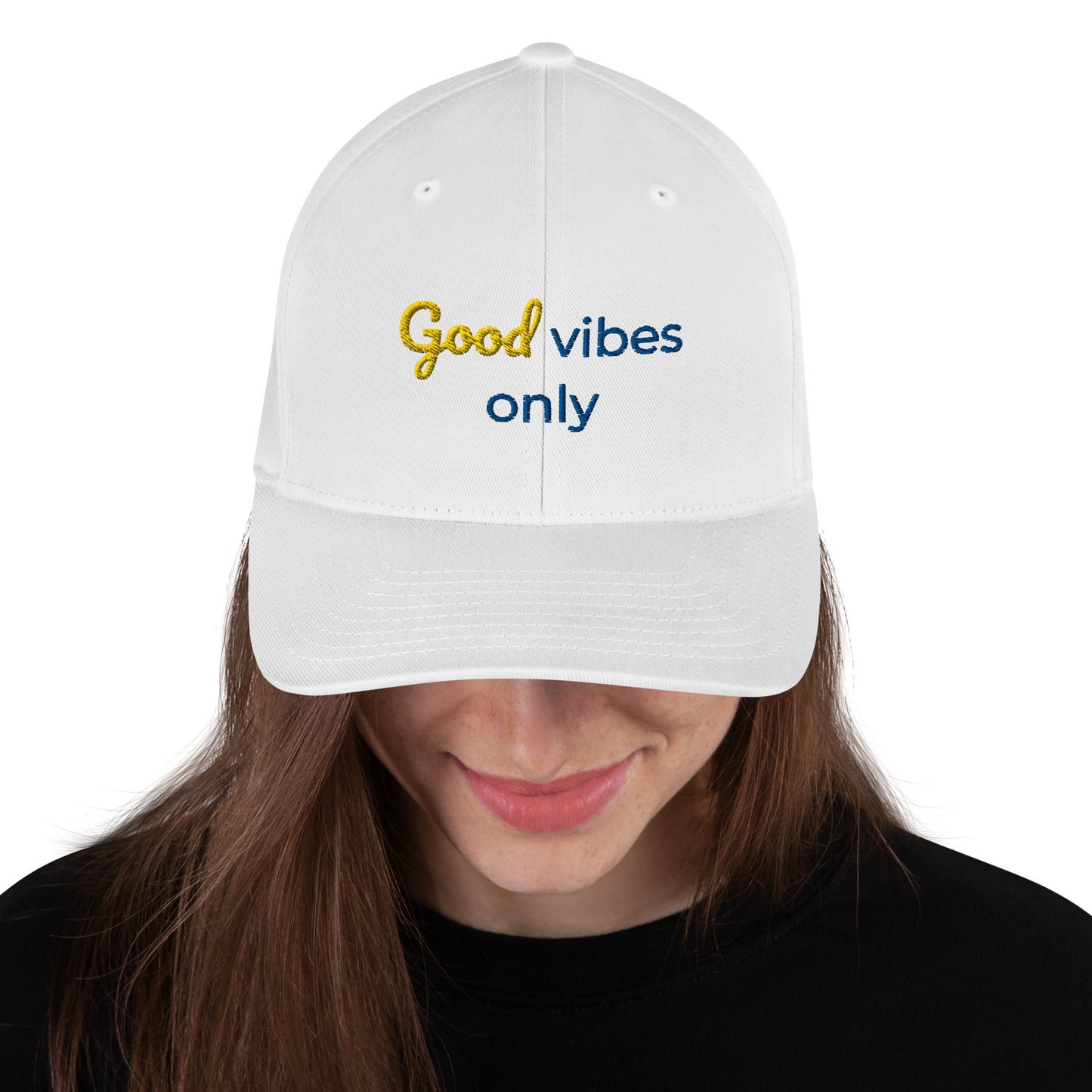 White baseball cap featuring embroidered text reading ‘GOOD VIBES ONLY’ in yellow, placed beside black headphones and stationery—modern, stylish, and perfect for casual wear.