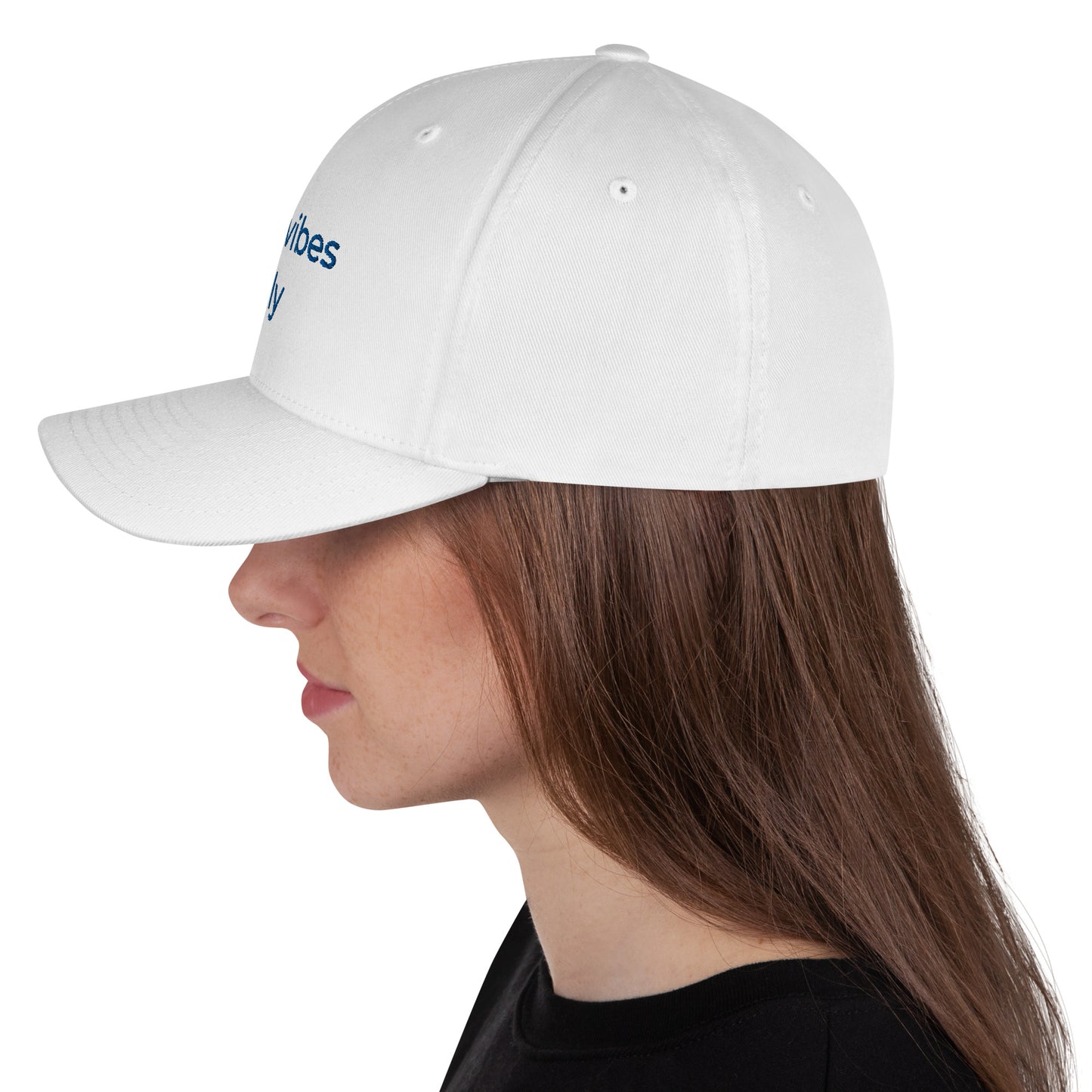 White baseball cap featuring embroidered text reading ‘GOOD VIBES ONLY’ in yellow, placed beside black headphones and stationery—modern, stylish, and perfect for casual wear.