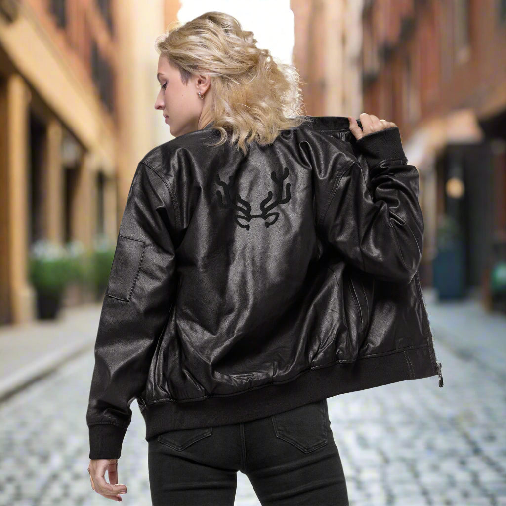 Black faux leather jacket with ribbed cuffs and hem, a zip-up front, soft grey inner lining, and a small embroidered deer logo on the chest—stylish, structured, and perfect for casual or dressy outfits.