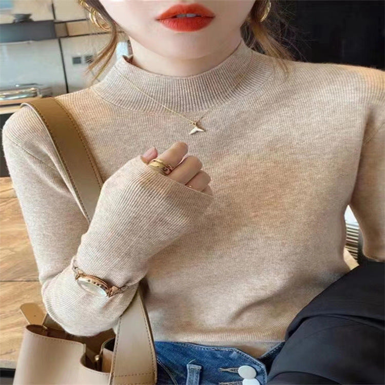 Woman wearing a ribbed light-colored turtleneck sweater, accessorized with hoop earrings, a delicate necklace, and rings—cozy, elegant, and perfect for chilly days.