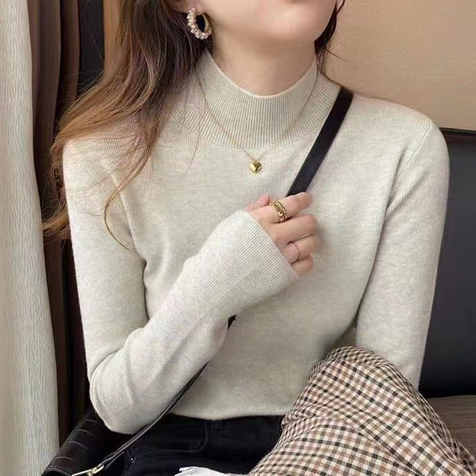 Woman wearing a ribbed light-colored turtleneck sweater, accessorized with hoop earrings, a delicate necklace, and rings—cozy, elegant, and perfect for chilly days.