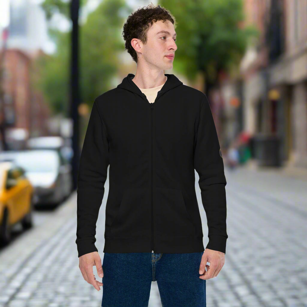 Person wearing a black zip-up hoodie featuring brushed fleece inside, kangaroo pockets, and a hood with matching drawstrings, paired with blue jeans—modern, comfortable, and perfect for athleisure styling.