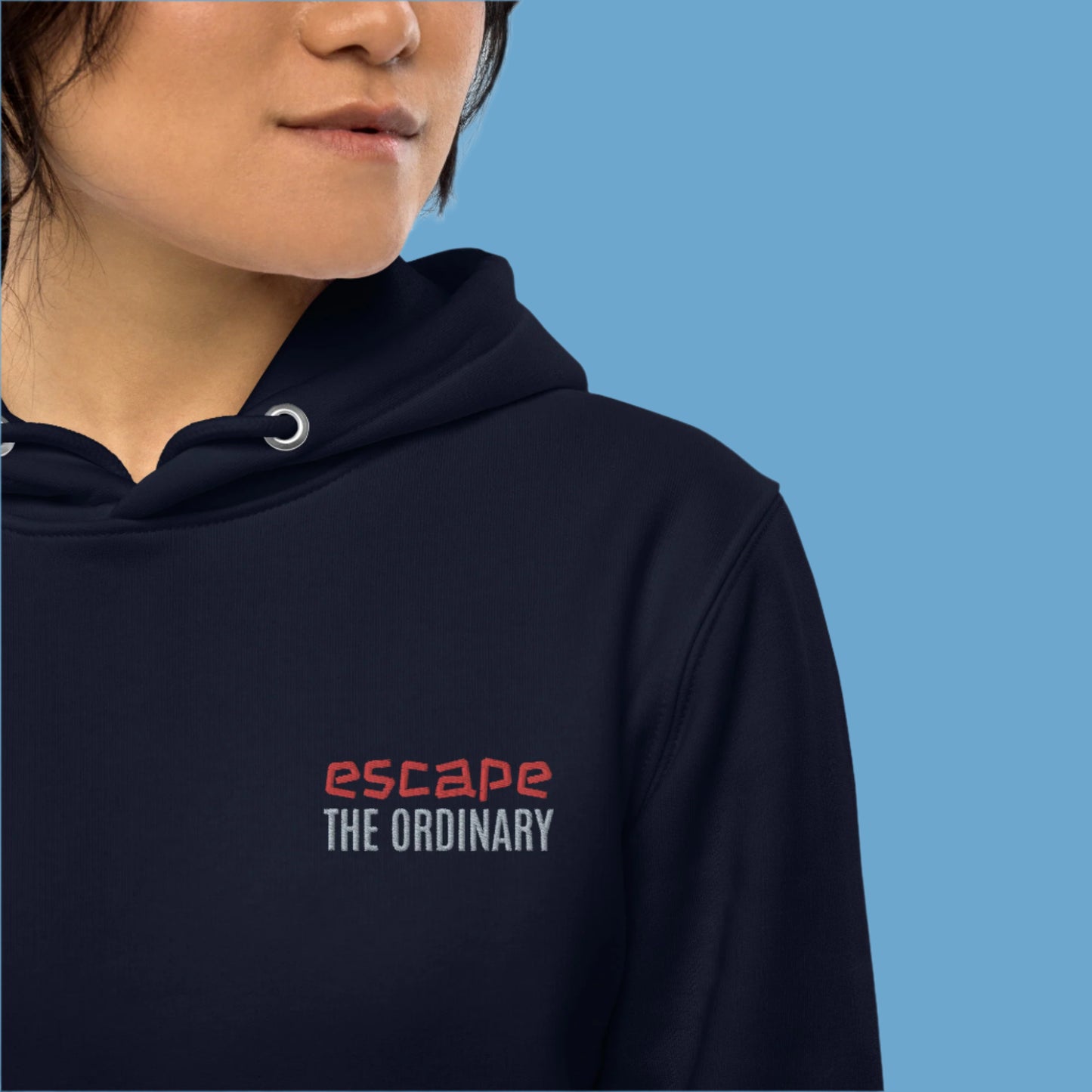 Minimalist street-style hoodie available in navy blue, black, and white, featuring a bold text design on the chest reading ‘escape’ in red and ‘THE ORDINARY’ in white, along with a front pocket and adjustable metal-tipped drawstring hood.