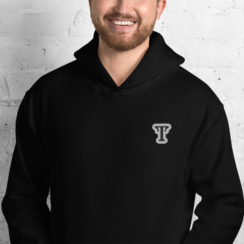 black hoodie featuring an embroidered letter ‘T’ on the left chest, worn against a white brick wall—modern, stylish, and available in Red, navy, and deep grey.