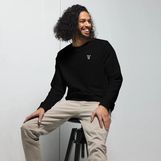 Black sweatshirt featuring an embroidered letter ‘T’ on the left chest, worn with beige pants, seated on a black stool against a white background—modern, stylish, and available in black, deep charcoal grey, and French navy.