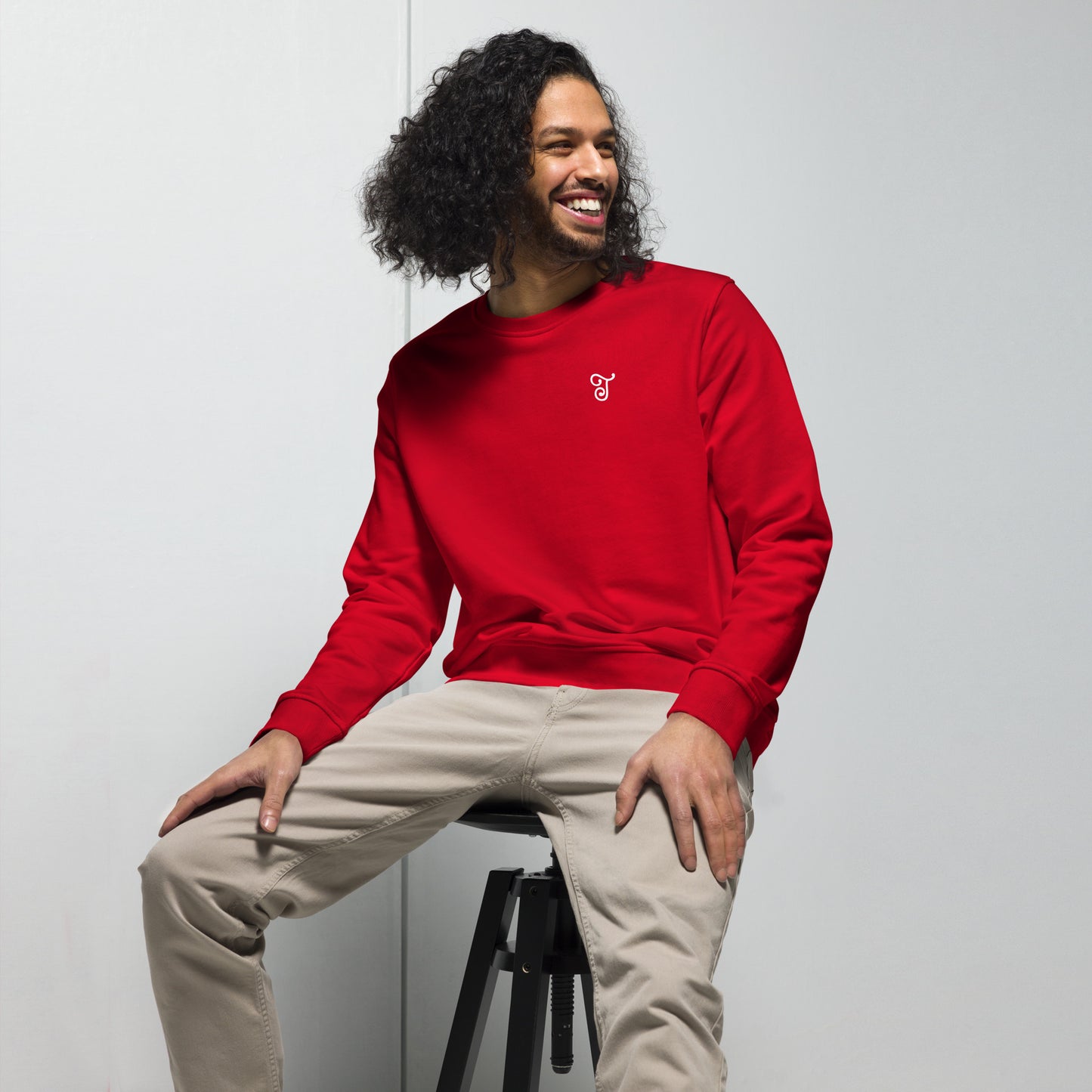 Red sweatshirt featuring an embroidered letter ‘T’ on the left chest, worn with beige pants, seated on a black stool against a white background—modern, stylish, and available in black, deep charcoal grey, and French navy.