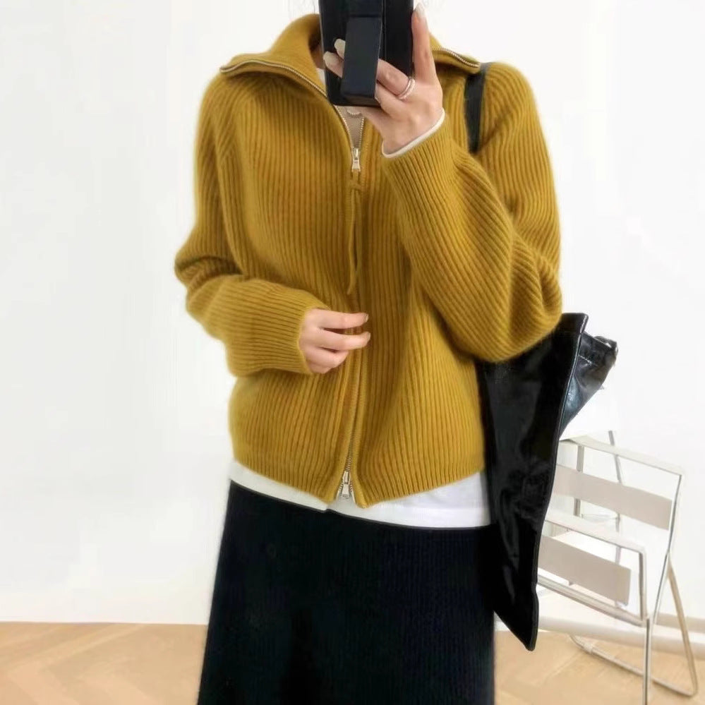 Woman wearing a yellow mustard ribbed knit sweater with a high collar and a partially zipped front, styled with light pink pants and delicate accessories—cozy, stylish, and perfect for layering.