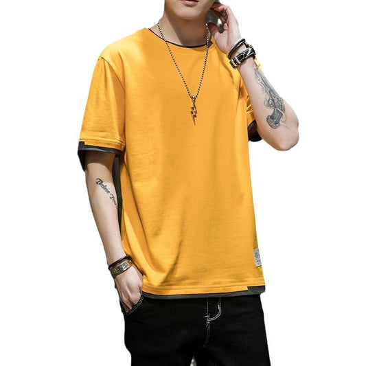 Person wearing a yellow t-shirt with white sleeve and hem accents, accessorized with a necklace, a watch, and bracelets, leaning casually against a dark textured wall—modern, stylish, and available in 8 colors.