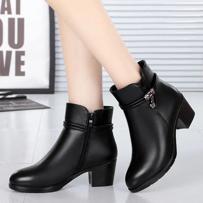 Black ankle boots worn by a person on a light gray background