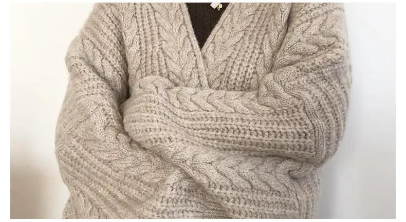 Close-up of a chunky cable-knit sweater in a light oatmeal beige color, worn by a model with arms crossed. The image includes a text overlay at the bottom detailing the collar design.