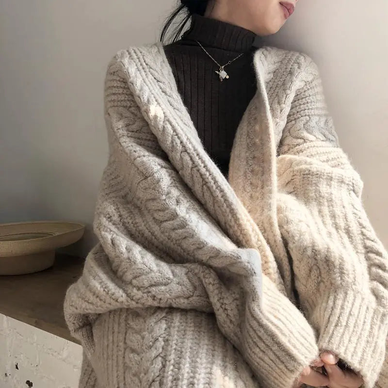 Person wearing a cozy beige knitted cardigan with a neutral background
