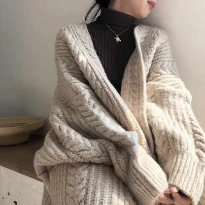 Person wearing a cozy beige knitted cardigan with a neutral background