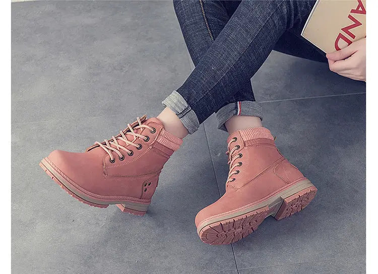 A pair of pink lace-up ankle boots worn with dark blue jeans, shown in two views on a gray tiled floor. The top view shows the boots from a side angle while the person sits, and the bottom view shows them from a top-down angle with a small card on the floor.