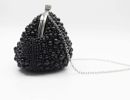 A black beaded evening clutch purse with a silver-tone metal clasp and a delicate silver chain strap, photographed on a clean white background.
