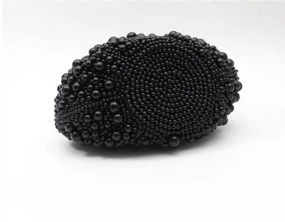 A black beaded oval clutch purse with a textured, raised bead pattern, photographed on a clean white background.